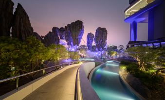 The city at night is illuminated with lights, showcasing a pool and bridge in the foreground at Grande Centre Point Space Pattaya