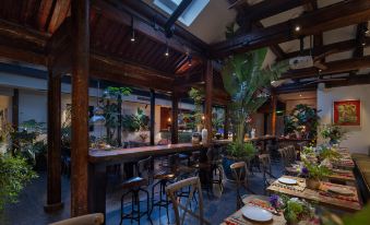 The restaurant is furnished with tables and chairs, and there are plants in the center area, while the other rooms are occupied at Peking  Yard Siheyuan Boutique Hotel(Garden&Terrace &Lama Temple&hutong&Houhai&Tiananmen&Restaurant
