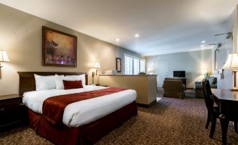 a large bed with a red blanket is in the middle of a room with a desk , chair , and television at Grand Vista Hotel