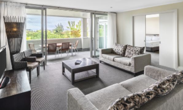 a modern living room with large windows and sliding glass doors leading to an outdoor patio at Hilton Lake Taupo
