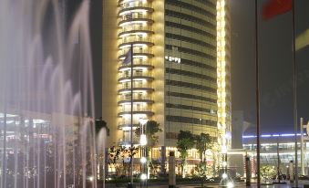 At night, a large building with fountains in front is illuminated, creating a picturesque scene at Best Western Premier Ocean Hotel