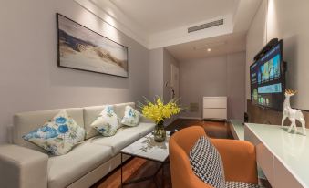 a modern living room with a white couch , an orange armchair , and a television mounted on the wall at Suisse Apartment Hotel Suzhou Jinji Lake Expo Center