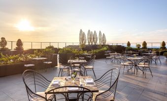 an outdoor dining area with tables and chairs set up on a rooftop , overlooking the ocean at Melia Vinpearl Hue