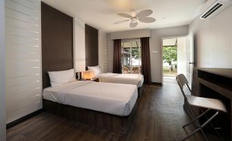 a hotel room with two beds , a desk , and a chair , all neatly arranged in the space at Perhentian Island Resort