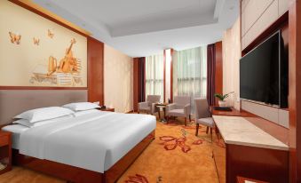 a hotel room with a king - sized bed , a flat - screen tv , a desk , and a chair at Mediterranean Hotel