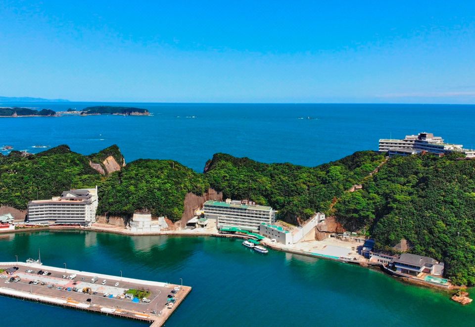 a beautiful coastal city with blue water , green trees , and buildings , as well as a view of the ocean from above at Hotel Urashima