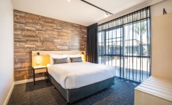 a modern hotel room with a large bed , wooden walls , and a balcony view of the city at Nightcap at Westside Hotel