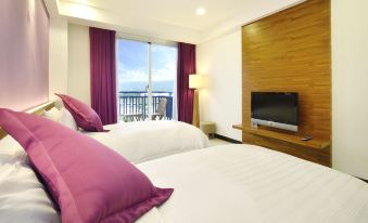 a hotel room with two beds , a tv , and a balcony view of the ocean at J Resort