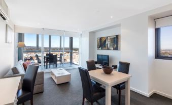 a modern living room with a dining table , chairs , and a large window overlooking the city at IStay Precinct Adelaide