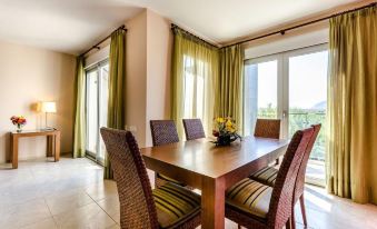 a dining room with a wooden dining table , four chairs , and a television mounted on the wall at El Plantío Golf Resort