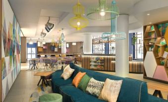 a modern lounge area with a blue couch , colorful pendant lights , and other decorative elements at Hampton by Hilton Rome North Fiano Romano
