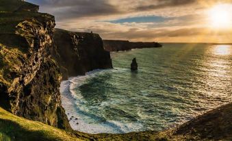 a dramatic view of the irish landscape , with cliffs and water cascading over them , under a cloudy sky at Hotel Doolin