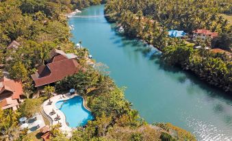 aerial view of a resort with a large body of water surrounded by lush greenery , including trees and bushes at Loboc River Resort