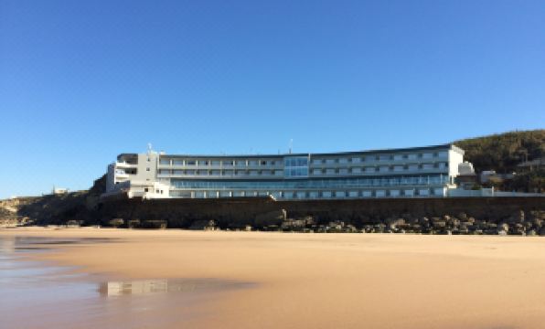 a beach scene with a large hotel in the background and a sandy beach in the foreground at Arribas Sintra Hotel