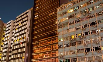 At night, a brightly lit large building in the city, featuring an office tower and various commercial establishments, creates a vibrant and bustling atmosphere with its many windows at Burlington Hotel