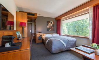 a cozy bedroom with a large bed , a desk , and a window overlooking the outdoors at Van der Valk Volendam