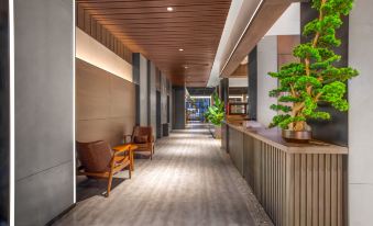 a long hallway with a wooden ceiling and chairs on either side , leading to an outdoor area at Mehood  Lestie Hotel
