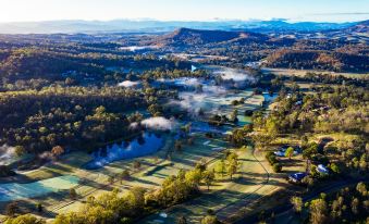 an aerial view of a serene countryside landscape with a river , trees , and mountains in the background at The Kooralbyn Valley