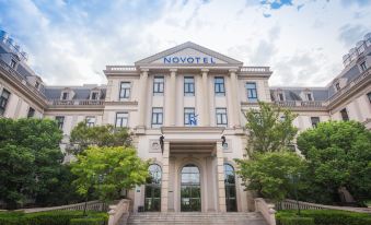 The front entrance of a large, modern building features an ornate stone facade and brick at Novotel Shanghai Hongqiao exhibition center hotel