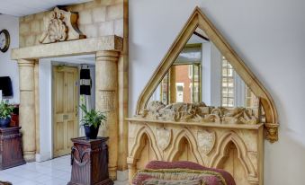 a room with a wooden arch and a chair , next to a potted plant on a table at Empire Hotel