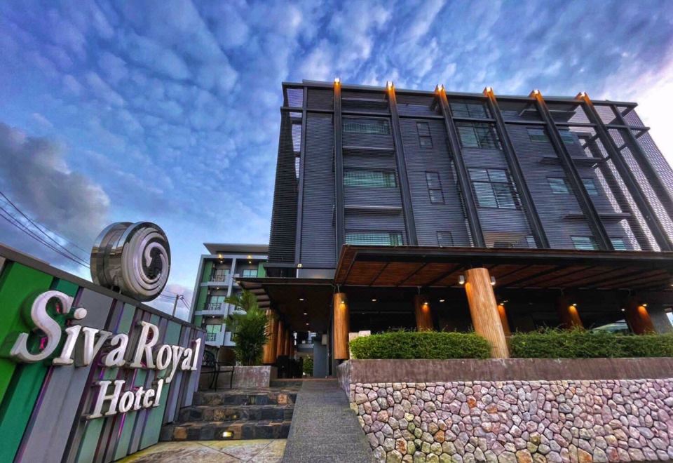 the exterior of the maya royal hotel with a sign and stone steps leading up to the entrance at Siva Royal Hotel