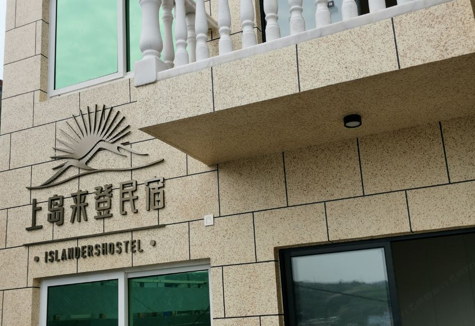 There is an intriguing sign above the front entrance of a hotel, with another building visible in the background at Shengsi wolfberry island on the island to the fisherman's family