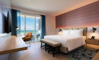 a luxurious hotel room with a large bed , white bedding , and a view of the ocean at Alma Resort Cam Ranh