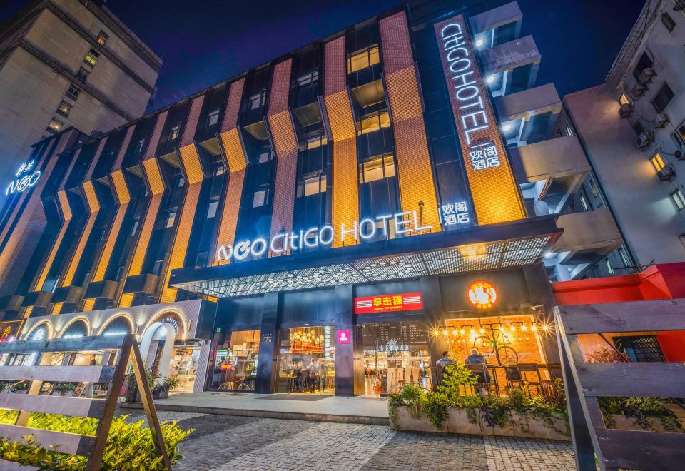 A building's front entrance in an urban setting is depicted at night at CitiGO Hotel, West Nanjing Road, Jing'an Temple, Shanghai