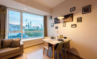 The living room features a small dining table and chairs, positioned near large windows that offer a view of the outside at Livefortuna Hotel