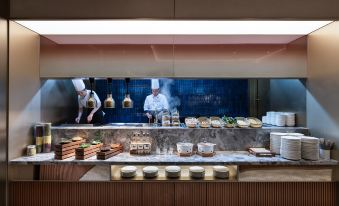 A man is standing at the counter of an Asian restaurant, both in front and behind, with food on it at Crystal Orange Shenzhen Nanshan Science and Technology Park