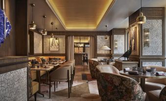 a modern , elegant dining room with wooden furniture and gold accents , including chairs , tables , and lamps at Four Seasons Hotel Madrid