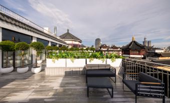 A rooftop balcony with chairs and tables provides a view of an outdoor seating area in front at Autoongo Hotel On the Bund, Shanghai