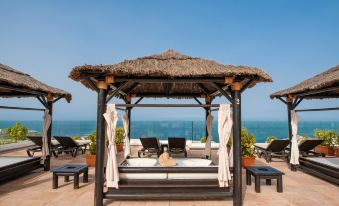 a resort with a large gazebo and several lounge chairs , providing a relaxing atmosphere near the ocean at Landmar Costa Los Gigantes