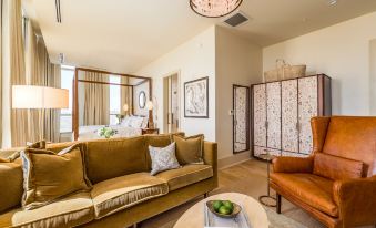 a living room with a brown couch , a wooden coffee table , and a large screen at The Dewberry Charleston