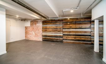 a large room with wooden walls and a brick wall has an exposed ceiling , concrete floor , and a gray floor at Air Venice on the Beach