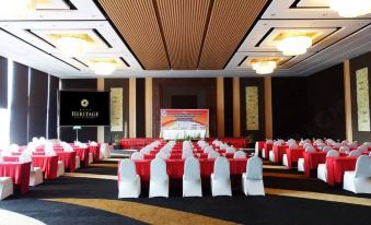 a large conference room with rows of red and white chairs arranged in an auditorium - like setting at Java Heritage Hotel Purwokerto