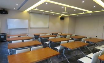 The photograph depicts an empty classroom with rows, a large screen at the front, and a row on the side at Ibis Styles Hotel (Beijing Capital Airport)
