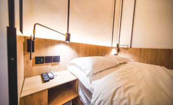 The room is equipped with a bed, a desk, and two lamps on each nightstand at POSHPACKER Local Tea Hostel