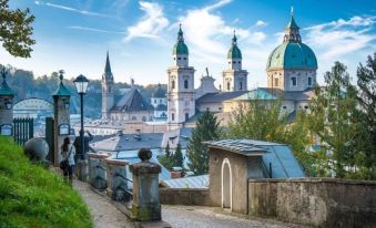 a view of a city with buildings and a church , taken from the perspective of a person walking up a staircase at Arte Hotel Salzburg