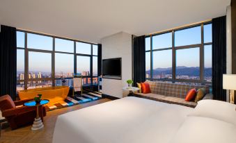 A modern bedroom with large windows and a balcony that overlooks the city, featuring an unmade bed at Kasion K Hotel Yiwu