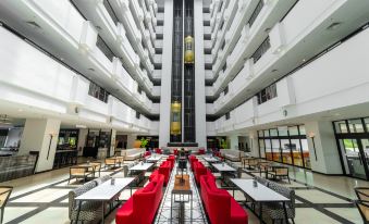 a large , modern hotel lobby with multiple dining tables and chairs arranged in an open area at Travelodge Ipoh