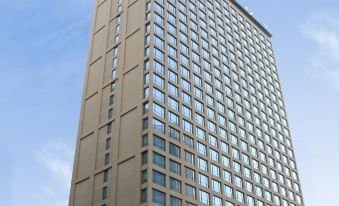 In front of an office tower, there is a tall building with many windows on its side at Courtyard by Marriott Shanghai Central