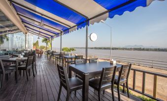 a dining area with a table and chairs , situated on a wooden deck overlooking a body of water at Blu Hotel