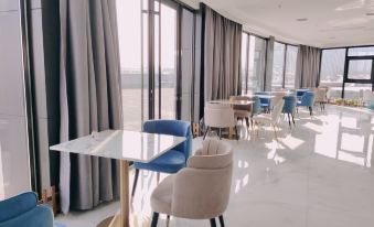 a modern , empty dining room with blue and white chairs , wooden tables , and large windows at Xuzhou Bo'an Hotel (University of Mining and Technology City Subway Station)
