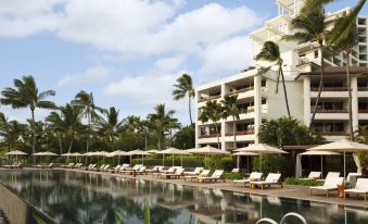 a large white building with a swimming pool in front of it , surrounded by palm trees at Four Seasons Resort Oahu at Ko Olina