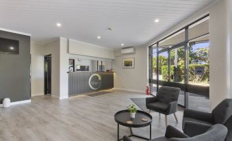 a modern office lobby with two black couches , a wooden floor , and a large window at The Wine Vine Hotel