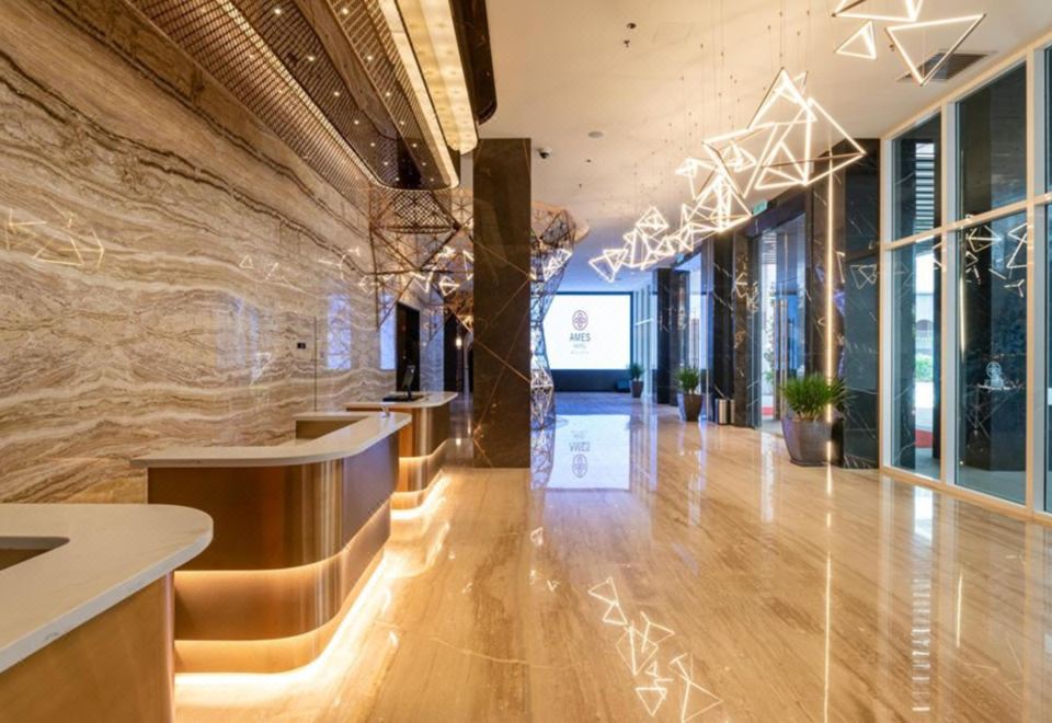 a modern hotel lobby with a reception desk and a large flat - screen tv mounted on the wall at Ames Hotel