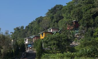 a row of small houses on a hillside , surrounded by trees and overlooking a body of water at Jsi Resort