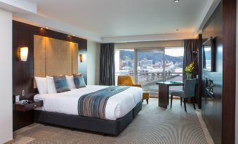 a large bed with white linens is in a room with a view of the water at Copthorne Hotel Wellington, Oriental Bay