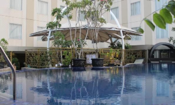 an outdoor pool surrounded by a patio area with a bar and chairs , creating a relaxing atmosphere at Sapphire Sky Hotel & Conference
